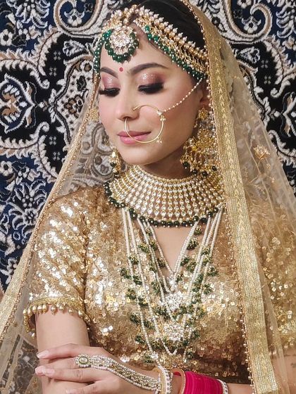 Another angle of the golden lehenga look, this time with the bride looking down, showcasing the heavy matha patti and earrings.