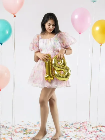 A full-length shot of the birthday girl in a lovely pastel dress, surrounded by balloons. This studio setup is perfect for a fun and stylish 18th birthday celebration.