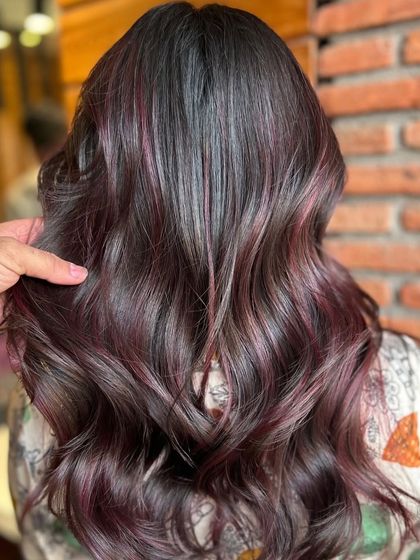 A close-up of these gorgeous soft highlights in a deep plum shade. This is a great way to add a touch of colour to dark hair without a drastic change, creating a subtle yet stunning effect when the light hits.