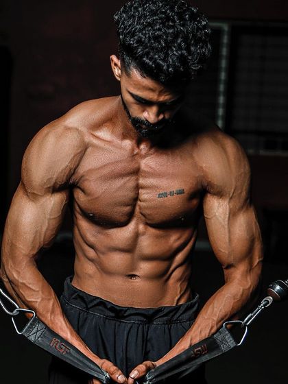 The final result of a 12-week prep. This client is performing a cable crossover, showcasing his shredded chest and defined abs.