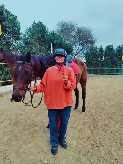A happy student with her horse and a medal, celebrating her progress in our training program.