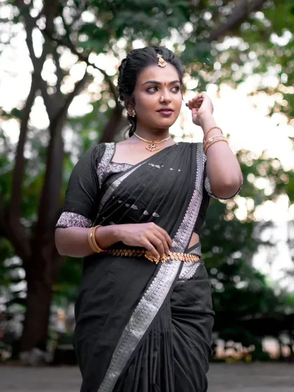 A beautiful outdoor portrait in a black saree. The natural background makes her traditional look stand out even more.