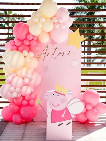 A pretty pink Peppa Pig themed birthday. This outdoor setup features a pink backdrop, a pink balloon garland, and a cute cutout of Peppa as a princess.