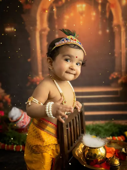 A close-up of the baby's mischievous and charming smile in his Krishna costume.