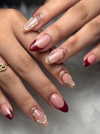 A sophisticated design with a deep red French tip and a gold chrome outline on a nude base. This look is modern, chic, and elegant.