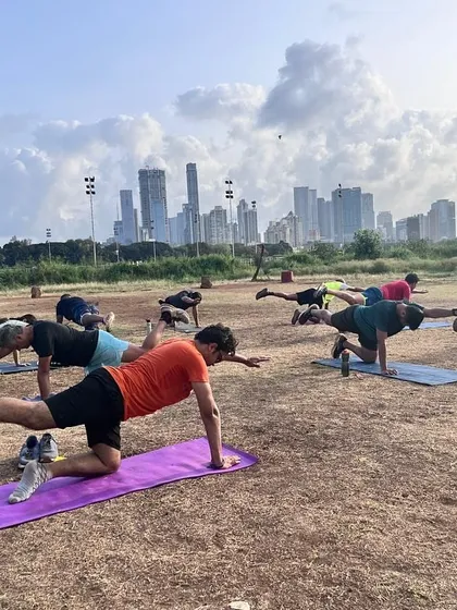 Our members working on their balance and core stability with bird-dog exercises at Mahalaxmi Racecourse, with the Mumbai skyline in the background.