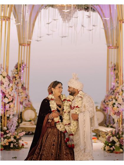 A beautifully composed shot of the couple at their beachside mandap, framed by elegant floral arrangements.