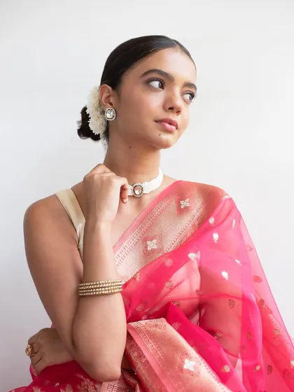 This angle shows the elegant low bun adorned with a white flower, a classic hairstyle that works beautifully with traditional sarees.
