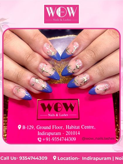 A bold and beautiful design featuring a deep blue French tip on a sheer base, adorned with golden star embellishments.