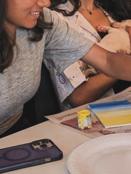 A close-up of a participant's art project with a puppy being cuddled in the background.