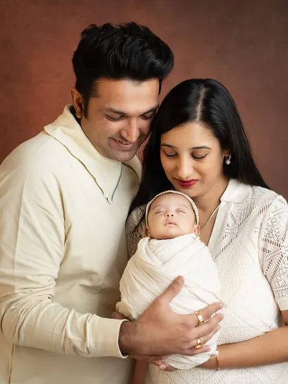 A beautiful portrait of new parents admiring their baby. The coordinated cream outfits create a soft and cohesive look.