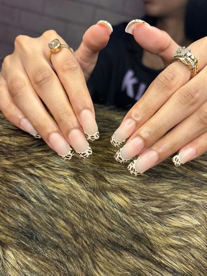 A fun take on the French manicure, these long square nails feature a trendy animal print pattern on the tips.
