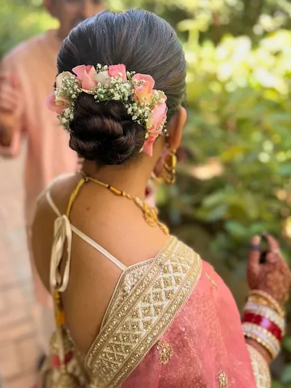 A beautiful braided bun adorned with fresh pink roses and baby's breath. This is a romantic and elegant hairstyle for a wedding or reception.