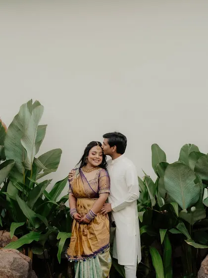 A sweet and simple portrait of a couple in a garden setting. The groom kisses the bride's forehead, a classic gesture of love and protection.