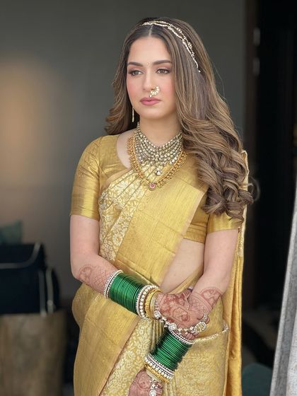 This portrait shows the complete traditional South Indian bridal look. The golden saree, temple jewelry, and radiant makeup come together to create a look of timeless elegance.