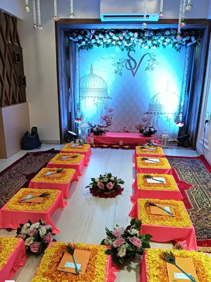 A wider view of the SV monogram setup, showing the complete arrangement for a ceremony. It includes low seating for guests on marigold-covered cushions, creating a traditional and welcoming space.
