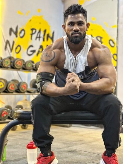 Focus on your goals. A seated pose showing a full and powerful upper body. The "No Pain No Gain" sign in the background says it all.