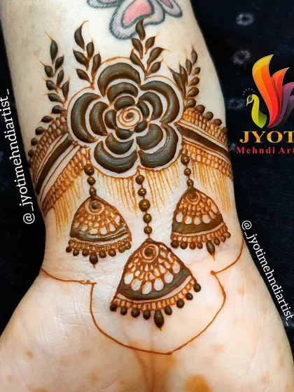 A beautiful wrist cuff design featuring a central flower with hanging jhumka (earring) motifs.