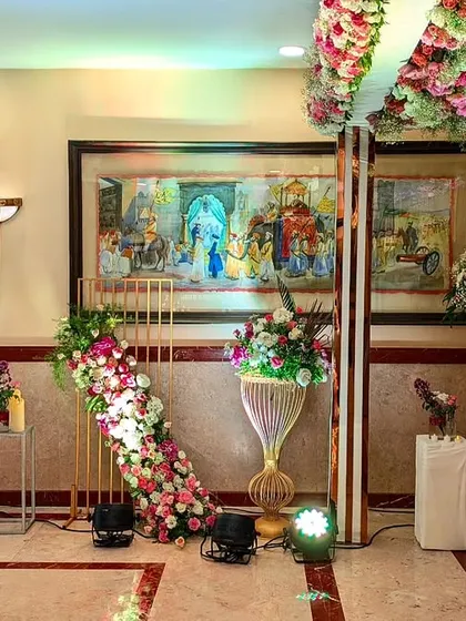A beautiful decor corner at The Lalit, where cascading florals and elegant vases are placed next to the venue's stunning traditional artwork.