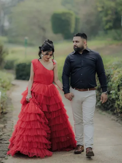 A candid moment within a cinematic shoot. As the couple walks hand-in-hand through a park path in Pune, her magnificent red dress adds a touch of drama to this otherwise natural interaction, blending two styles perfectly.