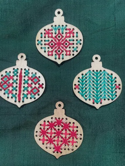 Embroidery can be done on many different surfaces, including these wooden ornaments. This is a fun way to create personalized decorations or gifts.