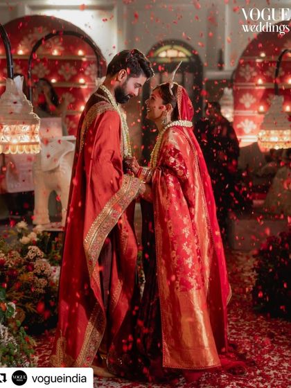 A romantic moment from Oishi and Arpit's wedding reception in Kolkata, featured in Vogue. The couple is showered in rose petals, surrounded by the warm glow of candles and traditional decor elements.