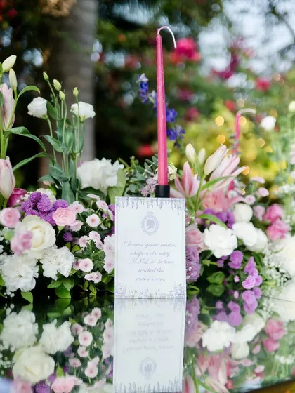 A detail shot of the table setting. Each place has a custom menu card, and the reflection on the mirror tabletop doubles the beauty of the floral arrangements and pink candles.