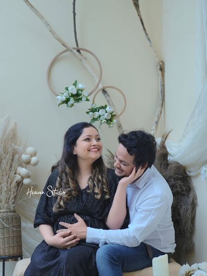 The comfort of being in each other's arms. This cozy studio portrait, set against a boho-chic backdrop, highlights the warmth and affection shared between the expecting parents.