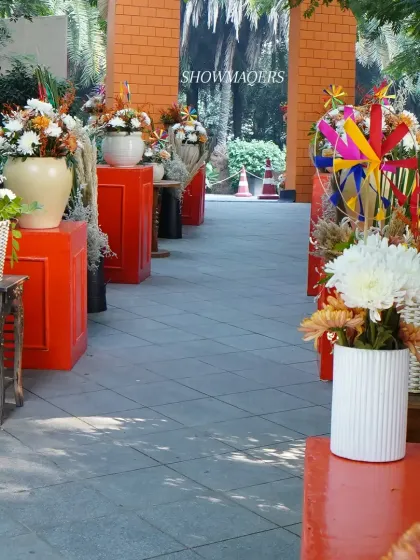 The entrance walkway lined with orange pedestals and floral arrangements, leading guests into the main event area.