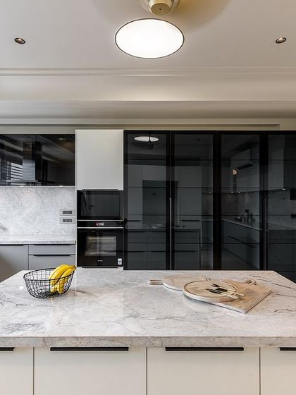 The kitchen's design incorporates a full-height unit with smoked glass doors, perfect for a pantry or crockery display, adding visual depth to the space.
