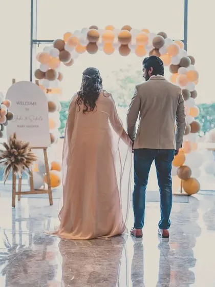 A 'We Can Bearly Wait' themed baby shower. This shot captures the parents-to-be standing before a custom balloon arch, ready to welcome their new arrival.