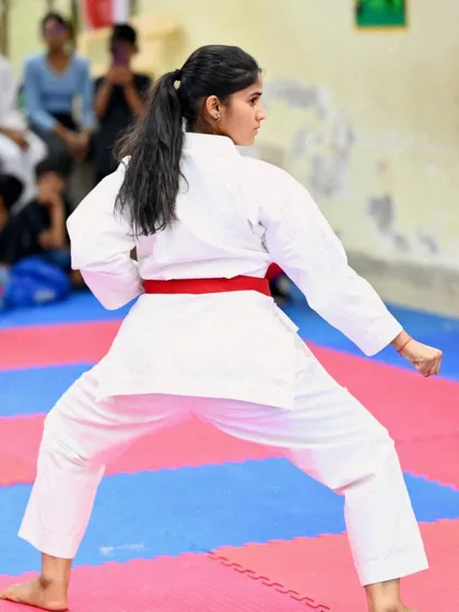 A rear view of a student in a deep stance, showcasing her stability and strength. A strong foundation is crucial for executing powerful techniques.