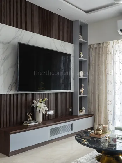 The television unit is often the centerpiece of a living room, and I design it to be a statement of style. This custom unit features a backlit Italian marble panel, handle-less drawers for a sleek look, and an integrated niche with a tinted mirror to display cherished art pieces.