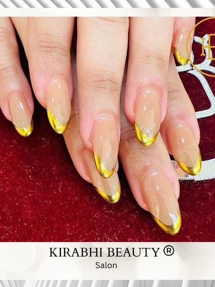 Elegance with an edge. These almond-shaped extensions feature a clear base with stunning gold chrome French tips for a luxurious and modern manicure.