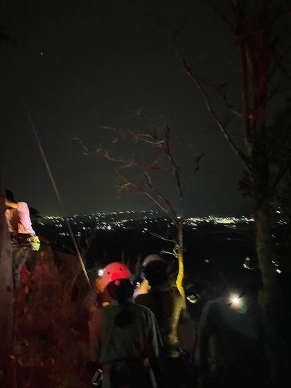 A stunning view of our climbers on the rock at night, illuminated by headlamps against the city lights below. Our full moon climbing sessions are a truly magical experience.