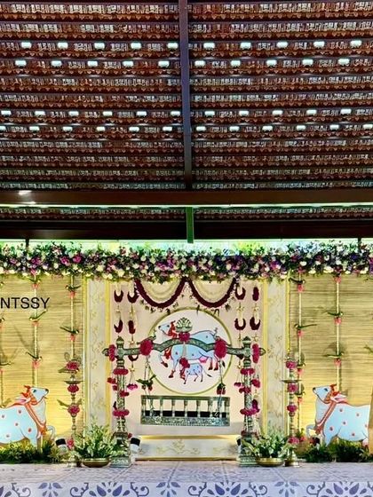 A wider view of the naming ceremony stage, showing the full backdrop with traditional motifs and floral arrangements. The setup is designed to be both grand and spiritually significant for the cradle ceremony.