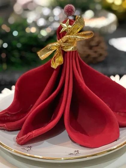 This Christmas napkin fold is designed to look like a festive tree, complete with a star on top. It's a charming and whimsical detail that adds a touch of holiday magic to each place setting.