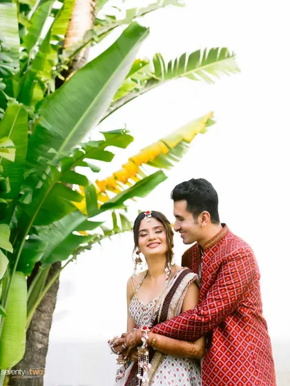 An intimate portrait of the couple nestled amongst giant banana leaves, a creative and natural framing that highlights their closeness.