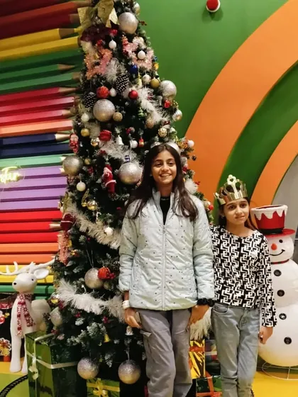 Two sisters pose in front of the Christmas tree and snowman, enjoying the holiday spirit at Tingaland.