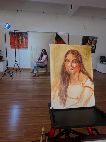 The portrait of Simran in progress on the easel, with a blue light source adding a cool tone to the setup. Experimenting with light is a key part of my process.