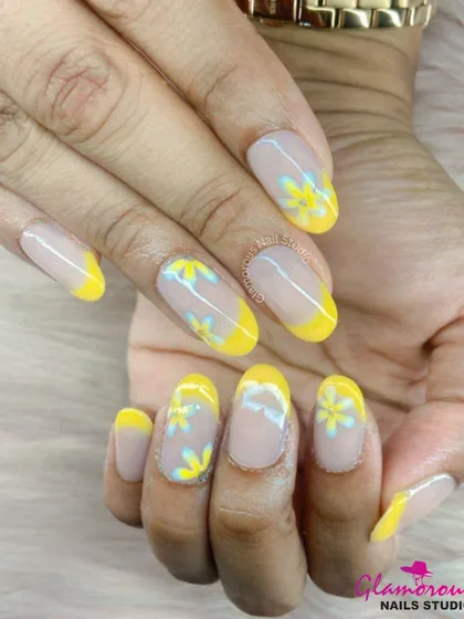 A cheerful and sunny design. We created a modern French manicure with bright yellow tips and added delicate, hand-painted yellow and blue daisies on the clear base for a fresh, floral look.