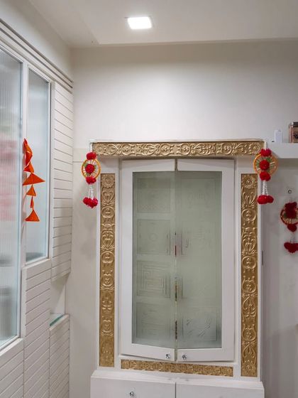 A simple decoration for a window or cabinet area, using a marigold garland and small handmade hangings to add a festive touch to the room.