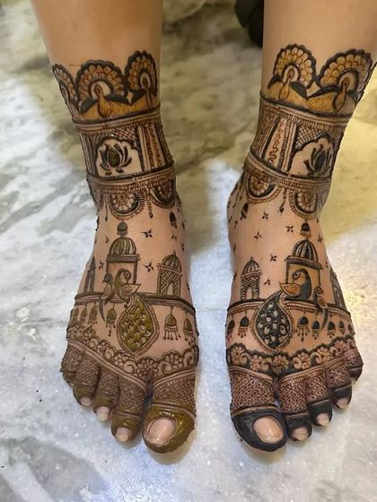 This design features jharokha windows with peacocks and hanging bells, giving the bride's feet a very traditional and ornate look.