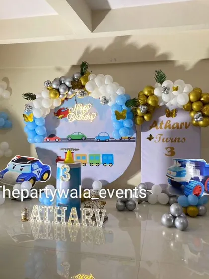 A vehicle theme party with cutouts of Thomas the Tank Engine and other cars. The blue, white, and gold balloon arrangements tie it all together.
