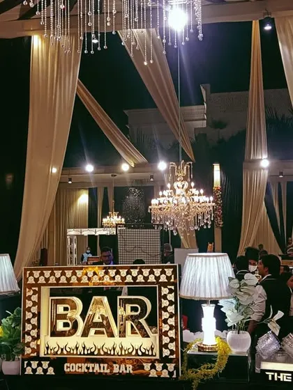 A wide shot of our bar setup in a beautifully draped wedding marquee, showing how our lighting and decor integrate seamlessly with the overall event design.