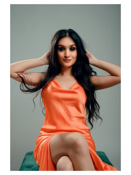 A glamorous portrait in a vibrant orange dress. The model's pose is confident and elegant, creating a striking image.