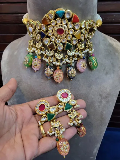 A vibrant Navratna-style kundan choker set, featuring multi-colored stones and hand-painted enamel drops. This unique piece is perfect for adding a pop of color to your mehendi or sangeet outfit.
