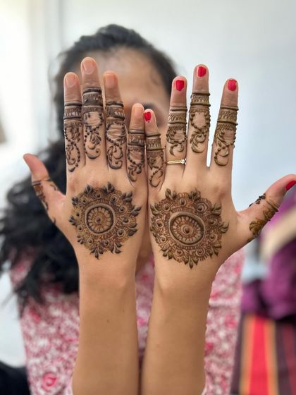 A simple and classic mandala design on the palms. The fingers are adorned with delicate vines and lines, creating a look that is both traditional and understated.