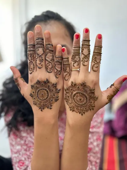 A simple and classic mandala design on the palms. The fingers are adorned with delicate vines and lines, creating a look that is both traditional and understated.