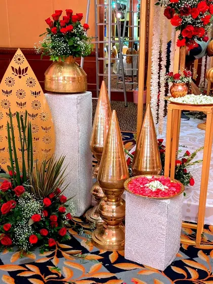 A corner of traditional elegance, featuring brass pots filled with red roses, ornate golden spires, and a laser-cut panel with a lotus motif.